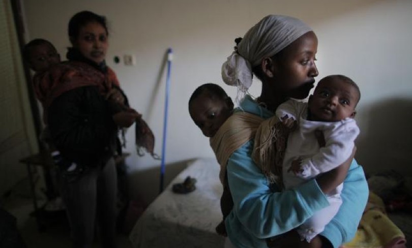 A woman holds two small children