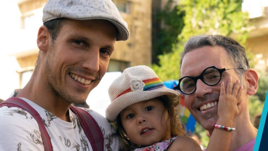 A gay couple holding their child.