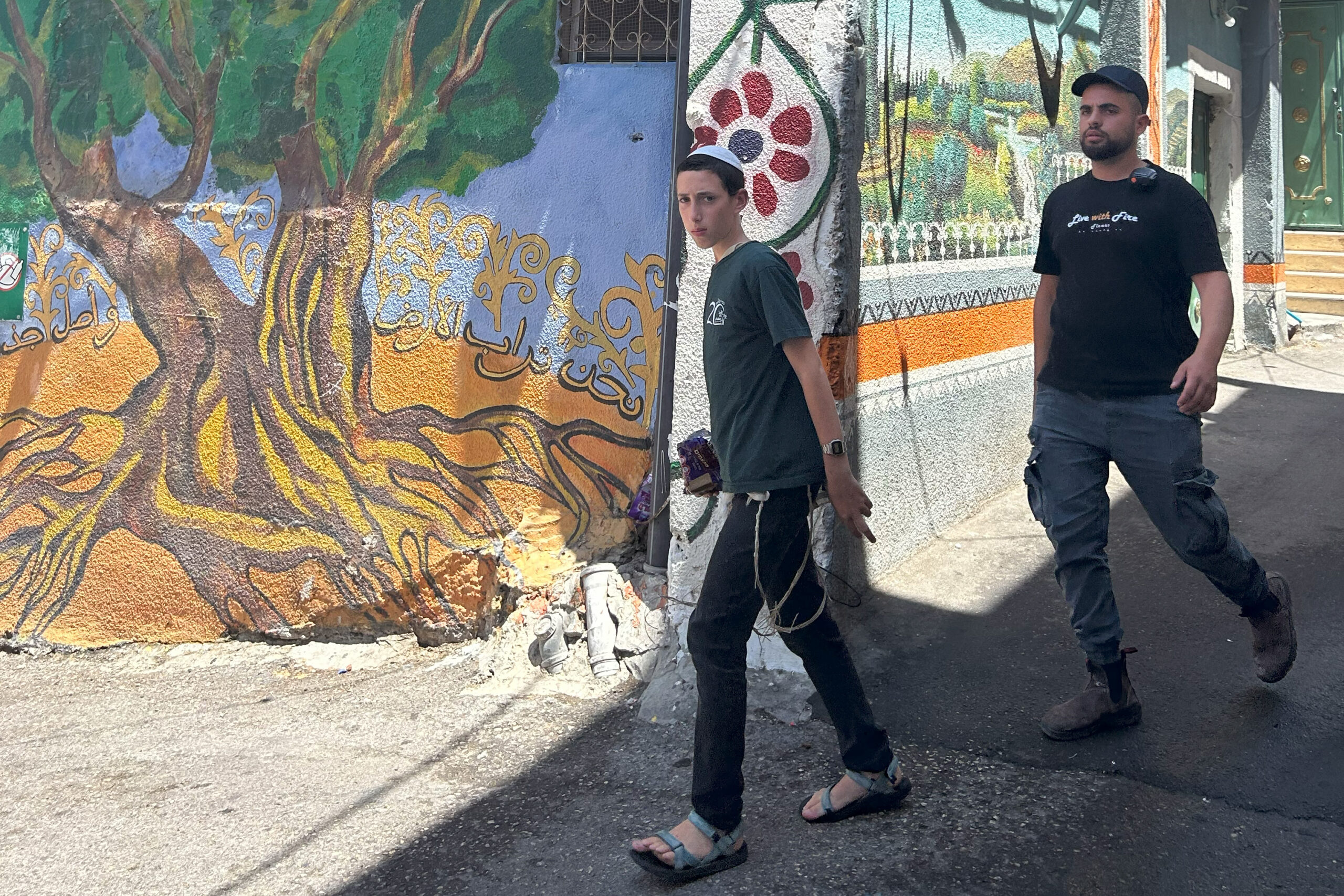 An armed guard with a settler boy in Silwan