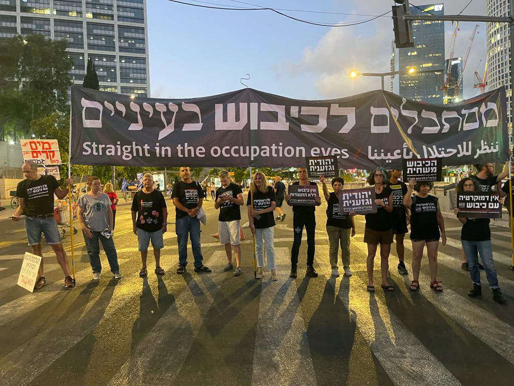Anti-Occupation protesters hold up a banner.