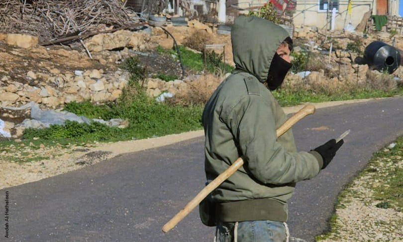 An Israeli Settler stands with his face covered in the West Bank