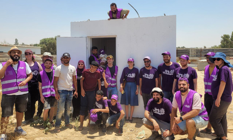 Standing Together volunteers gather around a mobile bomb shelter they installed in a Bedouin village