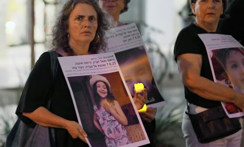 Activist Adi Argov holding a photo of a child killed by Israel in Gaza