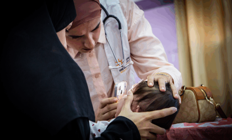 Doctors examine a child at a PHRI mobile clinic in the West Bank